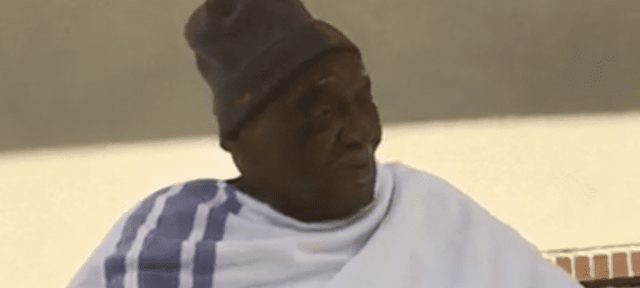 Elderly person wearing a beanie and shawl.